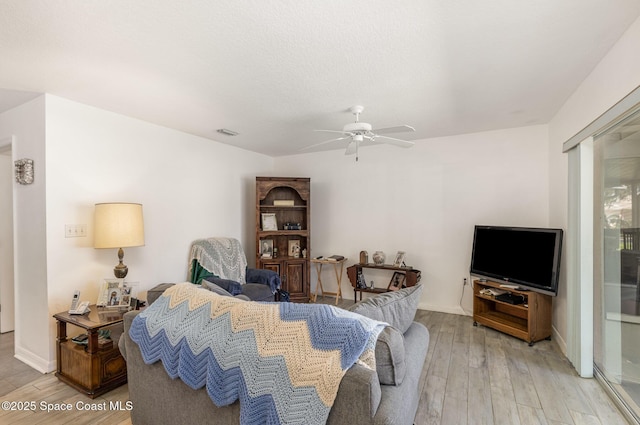 living area with a ceiling fan, visible vents, and light wood-style floors