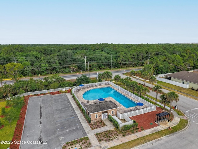 view of swimming pool featuring a wooded view
