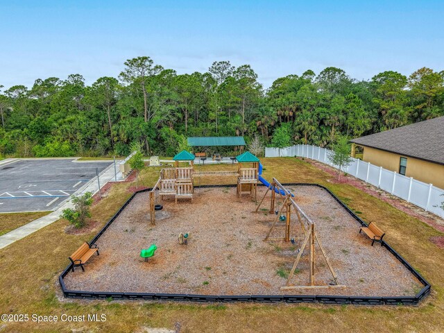 community playground featuring fence and a view of trees