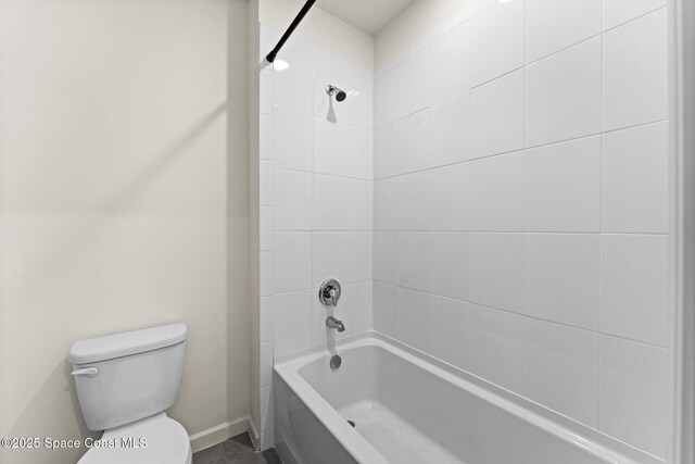 bathroom with baseboards, toilet, and  shower combination