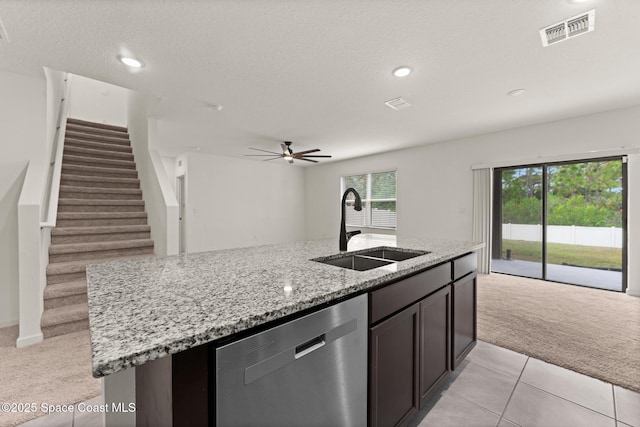kitchen featuring dishwasher, light carpet, a sink, open floor plan, and an island with sink