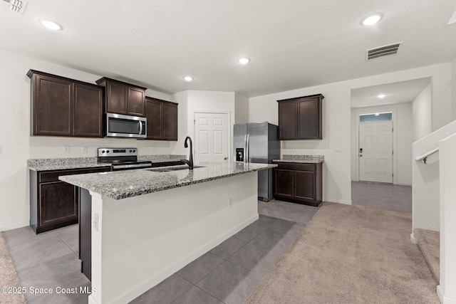 kitchen with appliances with stainless steel finishes, a sink, light tile patterned floors, dark brown cabinets, and recessed lighting