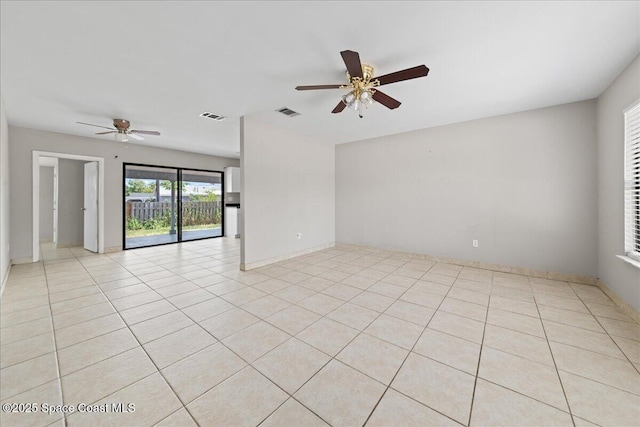 spare room featuring visible vents, a ceiling fan, and baseboards