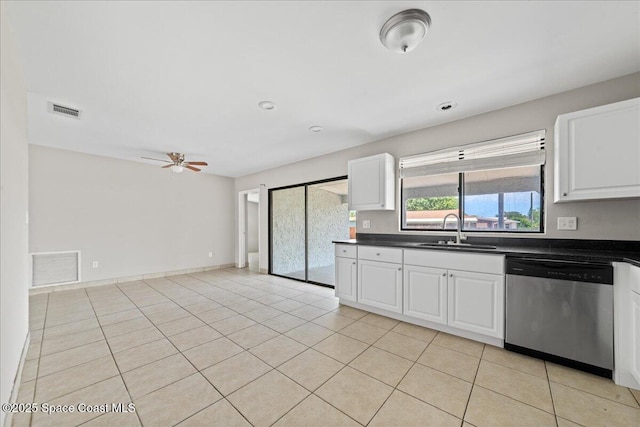 kitchen featuring stainless steel dishwasher, dark countertops, visible vents, and a sink