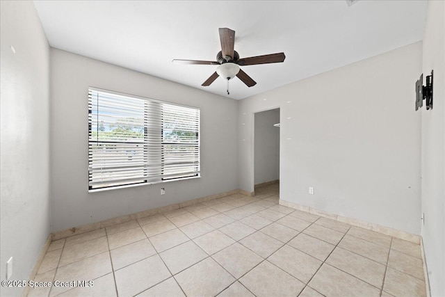 unfurnished room featuring baseboards, ceiling fan, and light tile patterned flooring