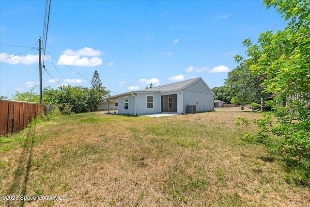rear view of house with a lawn, fence, and cooling unit