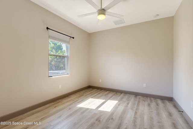 spare room featuring baseboards, ceiling fan, light wood-style flooring, and visible vents