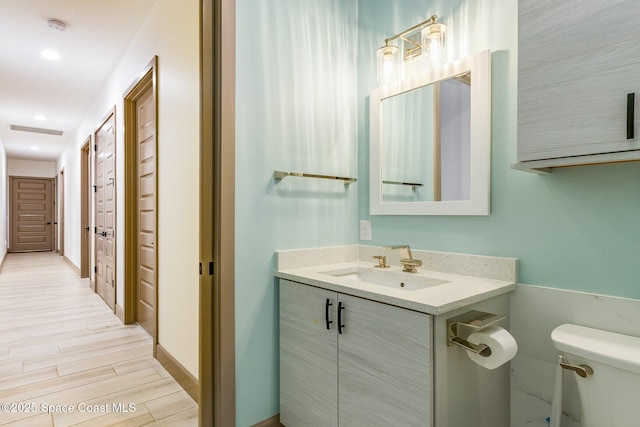 bathroom with vanity, wood finished floors, and toilet