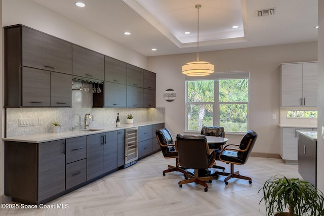 kitchen with a sink, beverage cooler, decorative light fixtures, decorative backsplash, and visible vents
