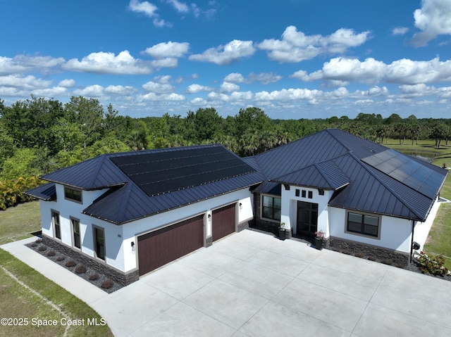 view of front of property featuring a garage, stucco siding, driveway, and metal roof