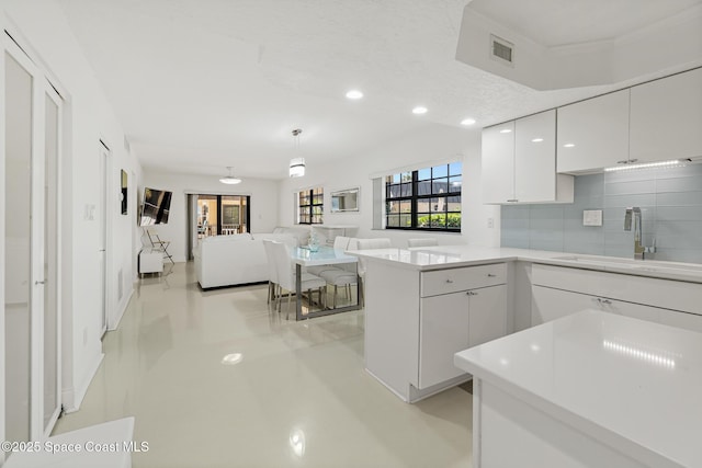 kitchen featuring a sink, white cabinetry, recessed lighting, backsplash, and a peninsula