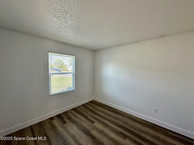 spare room featuring baseboards, dark wood-style flooring, and a textured ceiling