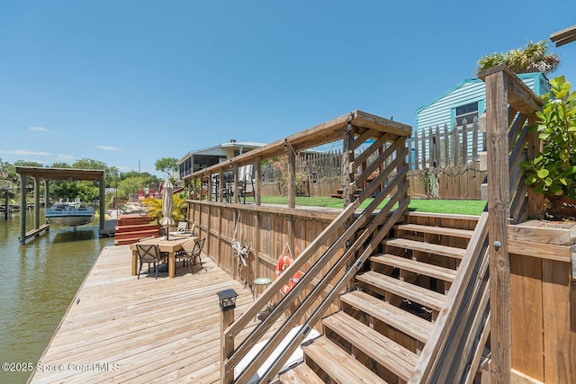 view of dock with fence, a water view, and stairway