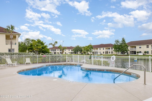 community pool with fence, a patio, and a residential view