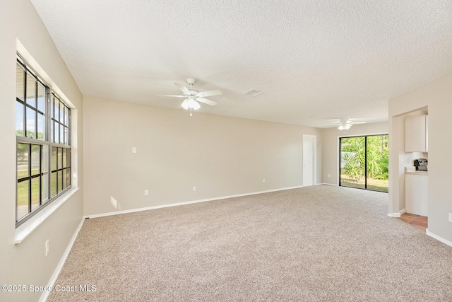 empty room featuring ceiling fan, light carpet, and a textured ceiling