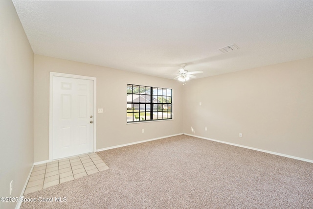 spare room with visible vents, baseboards, ceiling fan, and light carpet