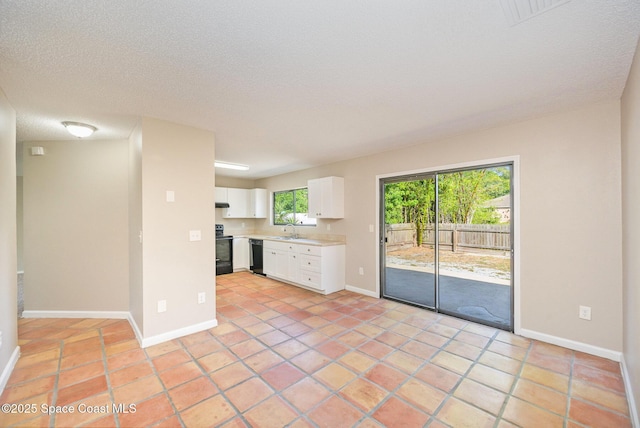 unfurnished living room featuring light tile patterned flooring, baseboards, a sink, and a textured ceiling