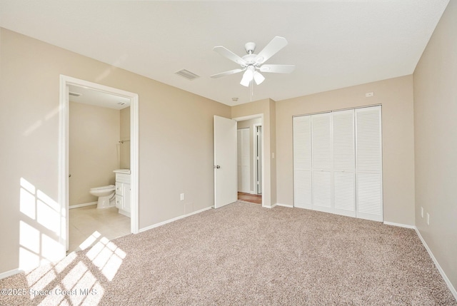 unfurnished bedroom featuring visible vents, a closet, baseboards, ensuite bathroom, and carpet flooring