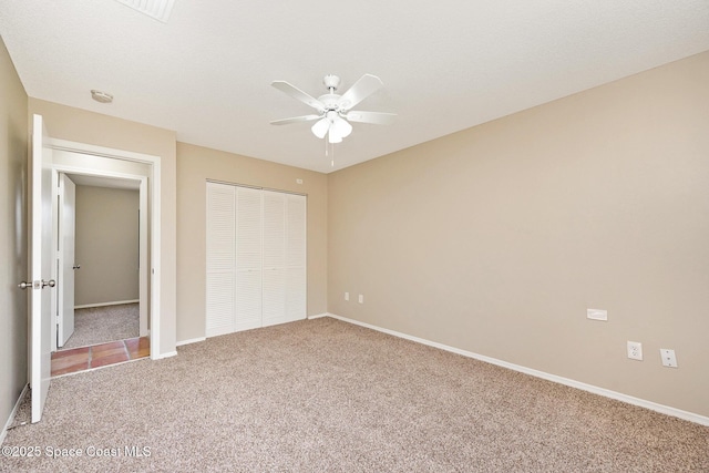 unfurnished bedroom featuring a closet, baseboards, a ceiling fan, and carpet flooring