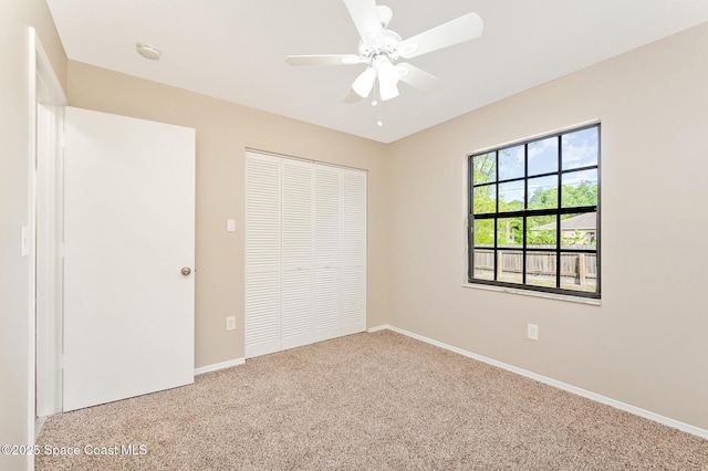unfurnished bedroom featuring carpet floors, baseboards, a ceiling fan, and a closet