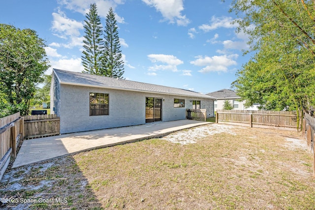 rear view of property featuring a fenced backyard, a patio area, stucco siding, and a yard