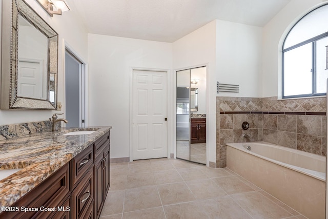 full bathroom featuring a wealth of natural light, tile patterned floors, a garden tub, and vanity