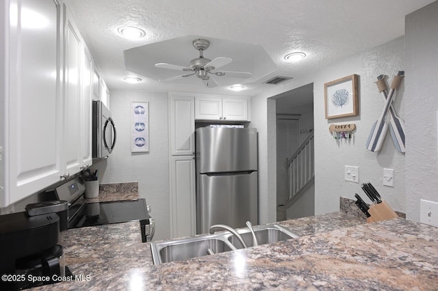kitchen featuring a sink, a textured wall, stainless steel appliances, and a textured ceiling