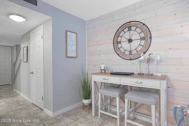 hallway with wooden walls, baseboards, stone finish floor, and visible vents