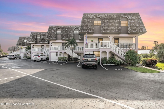 property at dusk with uncovered parking and stairway