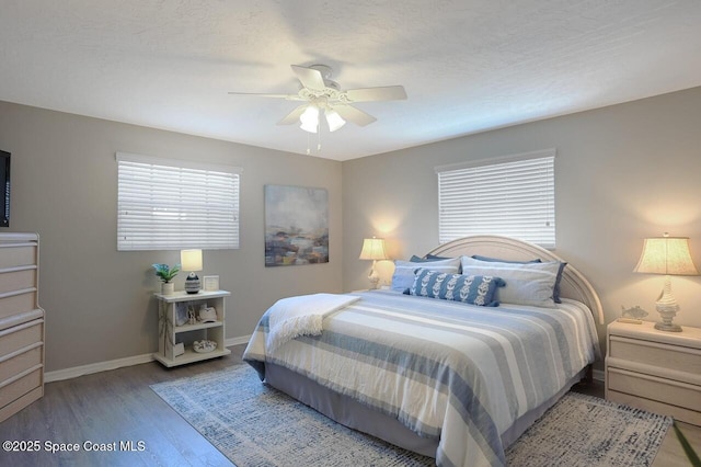 bedroom featuring baseboards, a ceiling fan, wood finished floors, and multiple windows