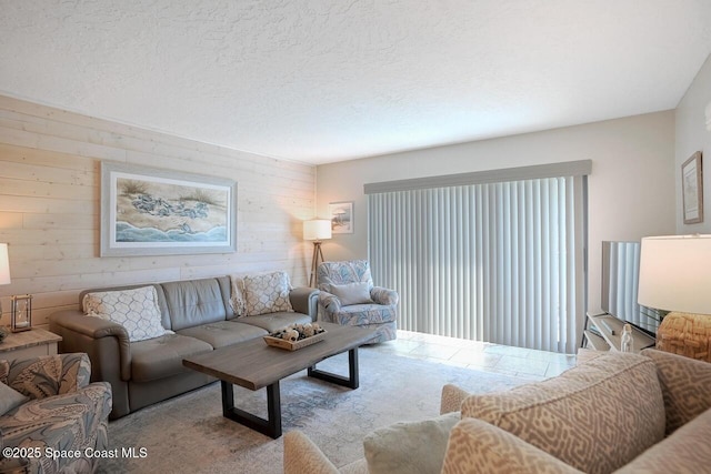 living room featuring wooden walls, a textured ceiling, and carpet