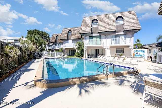 community pool with fence and a patio area