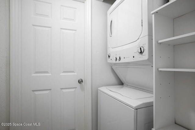 clothes washing area with stacked washing maching and dryer and laundry area