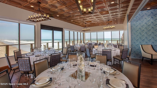 dining area featuring an inviting chandelier, a water view, an ornate ceiling, and wood finished floors