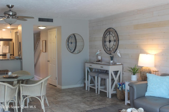 5350 Ocean Beach Blvd Unit 207, Cocoa Beach, FL 32931 - living room featuring wood walls, ceiling fan, a textured ceiling, and baseboards