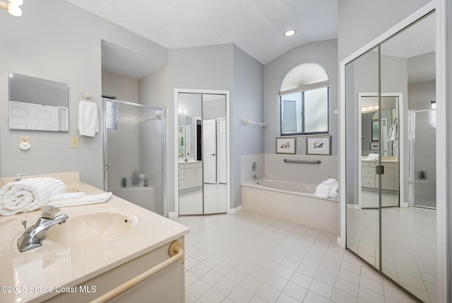 full bath with a shower stall, lofted ceiling, vanity, a garden tub, and tile patterned flooring