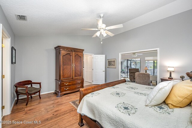 bedroom featuring light wood finished floors, baseboards, a ceiling fan, a textured ceiling, and high vaulted ceiling