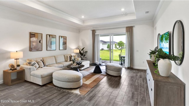 living area with ornamental molding, a tray ceiling, dark wood-style flooring, and visible vents