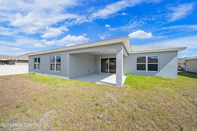 back of property featuring a lawn, a patio area, stucco siding, and fence