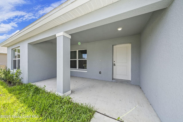 entrance to property featuring a patio and stucco siding