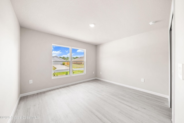 spare room featuring baseboards and wood finished floors