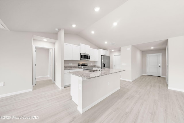 kitchen with white cabinets, a sink, light wood finished floors, stainless steel appliances, and a center island with sink