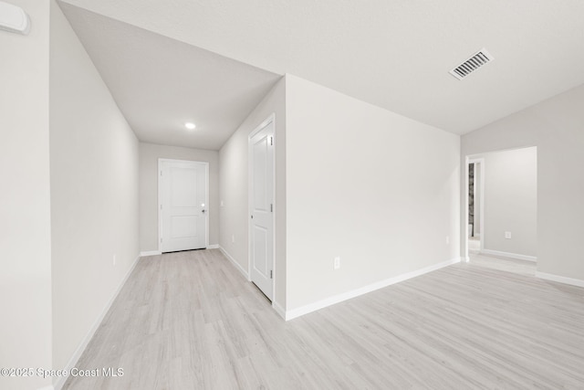 spare room featuring light wood finished floors, recessed lighting, baseboards, lofted ceiling, and visible vents