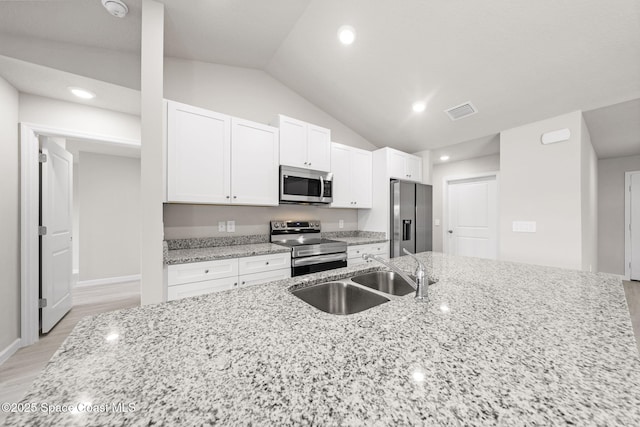 kitchen with visible vents, vaulted ceiling, a sink, stainless steel appliances, and white cabinetry
