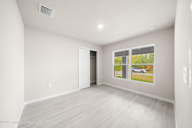 unfurnished bedroom with visible vents, a closet, wood finished floors, baseboards, and recessed lighting