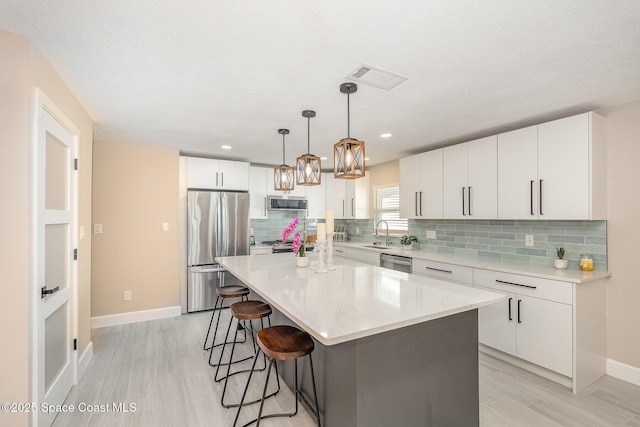 451 Bridgetown Ct, Satellite Beach, FL 32937 - kitchen with appliances with stainless steel finishes, a sink, a breakfast bar, baseboards, and tasteful backsplash