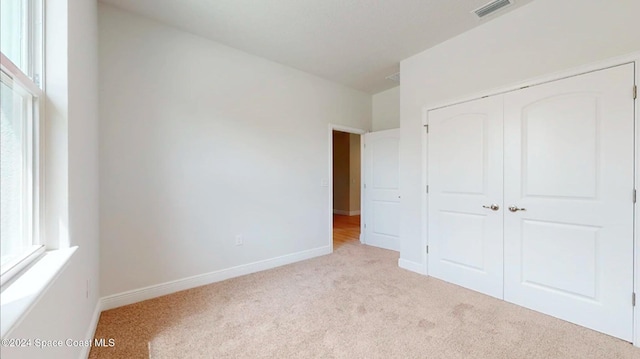 unfurnished bedroom featuring baseboards, carpet, a closet, and visible vents