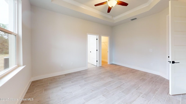 spare room featuring ceiling fan, visible vents, a wealth of natural light, and a raised ceiling