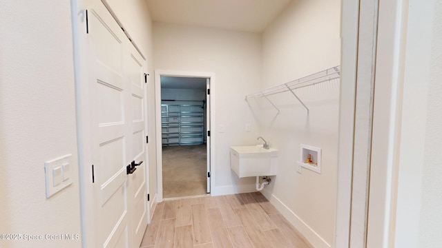 laundry area featuring washer hookup, baseboards, laundry area, and light wood finished floors