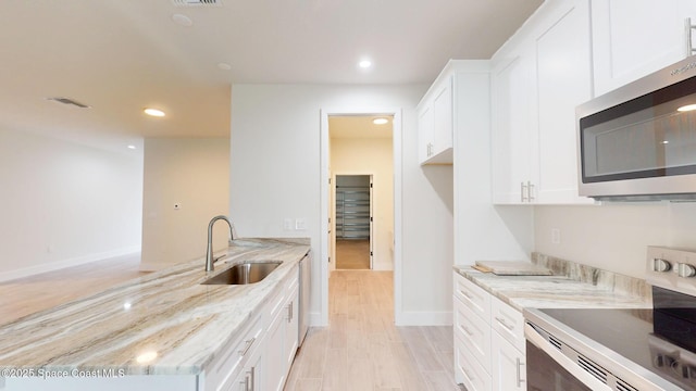 kitchen with recessed lighting, a sink, appliances with stainless steel finishes, and light stone countertops